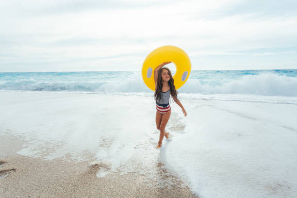 istock Cheerful girl playing with inflatable ring on the beach her summer vacation 2097600364