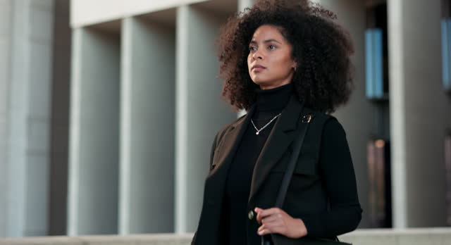 Business, black woman and walking by urban building with thinking and serious for morning travel or journey outdoor. Assertive, person with afro and corporate worker moving to work in city or town