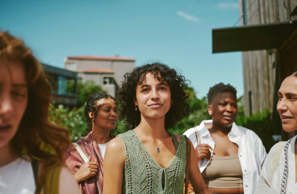 Young woman standing with friends after a yoga class at a wellness retreat Smiling young woman standing with friends outside after a yoga class on a patio at a wellness retreat in the summertime group of people standing together stock pictures, royalty-free photos & images
