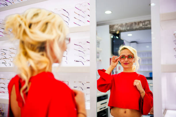 istock Smiling young woman trying on glasses on mirror in optician 2097663241