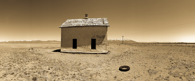 Abandoned House in Desert, Old Tire Out Front, in Sepia