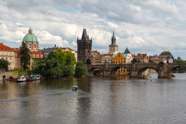 The Charles Bridge (Karluv most), the water clock tower, the old town bridge tower over Vitava river and the large dome of St francis of assisi church in Prague, Czech Republic.