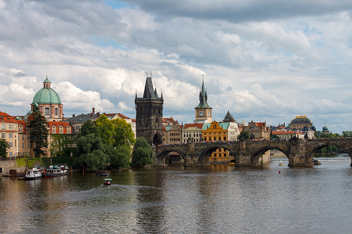 The Charles Bridge (Karluv most), the water clock tower, the old town bridge tower over Vitava river and the large dome of St francis of assisi church in Prague, Czech Republic.