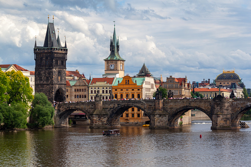 The Charles Bridge (Karluv most), the water clock tower, the old town bridge tower over Vitava river and the large dome of St francis of assisi church in Prague, Czech Republic.