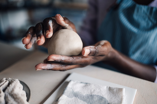 Pottery maker, artist or designer molding and building an object with clay at a factory, studio or art class. Worker, ceramist or potter creating, designing or making a structure at a workshop