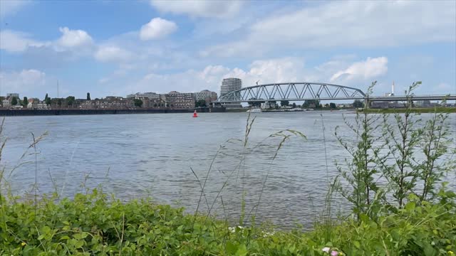 Timelapse of The Nijmegen railway bridge in the background on River Waal connecting the city of Nijmegen to the town of Lent in the Netherlands, Europe