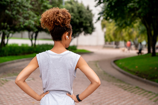 Rear view of a woman exercising at a public park and listening to music with headphones