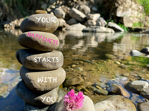 Your happiness starts with you text on stacked rocks background. Stock photo.