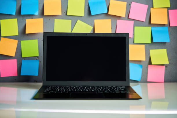 istock Modern laptop and blank colorful sticky notes on wall background 2097857566