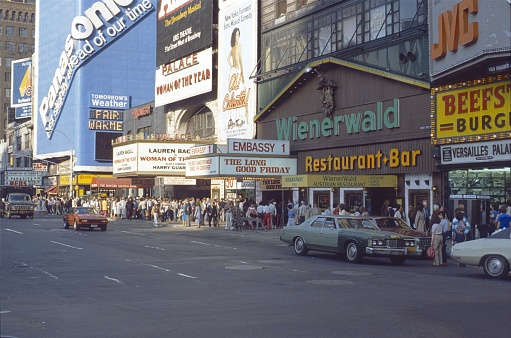 New York City, NY, USA, 1977. Street scene in busy Times Square in downtown Manhattan. Furthermore: tourists, visitors, music theaters, cinemas, restaurants and traffic.