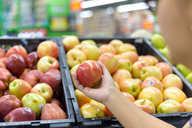 istock Hand holding an apple at a supermarket. 2097878787