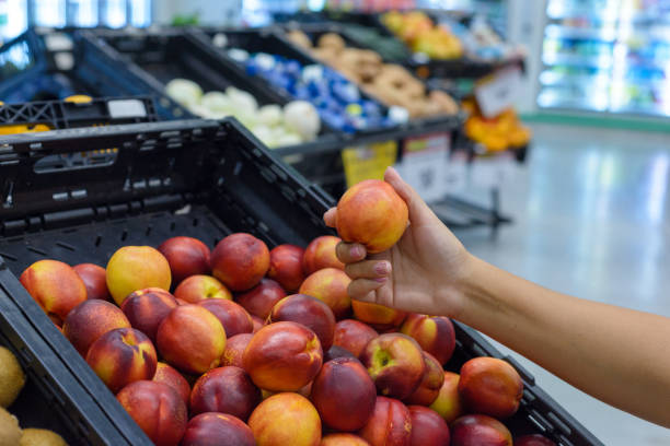 istock Hand holding a nectarine in a supermarket. 2097879306