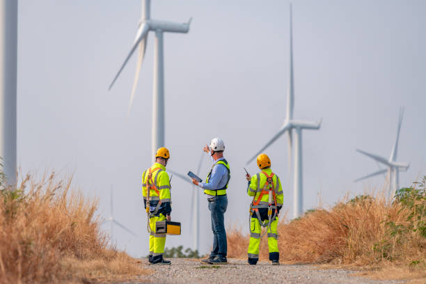 istock Engineer surveyor and manager wearing uniform walking holding box inspection and tablet work in wind turbine farms rotation to electricity, alternative renewable energy for clean power energy concept 2097981643