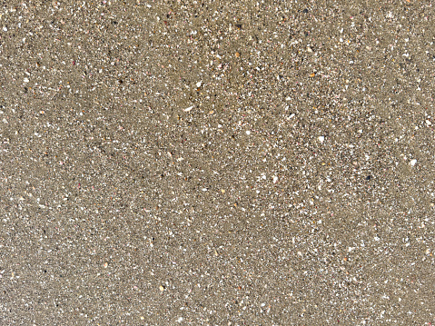 Pattern of sand with wet surface with white shells and stones