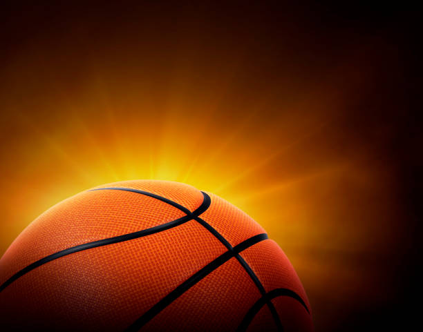 istock basketball ball. on black background with smoke, yellow orange red white colored back lights 2098029656