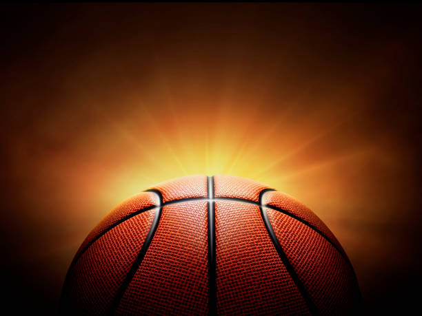 istock basketball ball. on black background with smoke, yellow orange red white colored back lights 2098029659