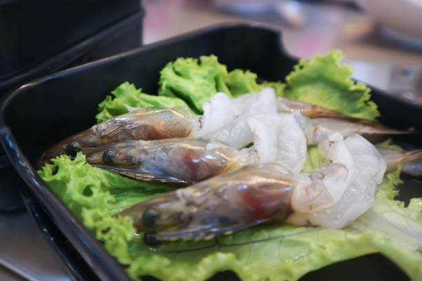 Four fresh river prawns placed neatly on  white square plate, ready for cooking. Concept, seafood ingredient for gourmet dishes. Thai cuisine, or grilling. Perfect for food lovers and culinary