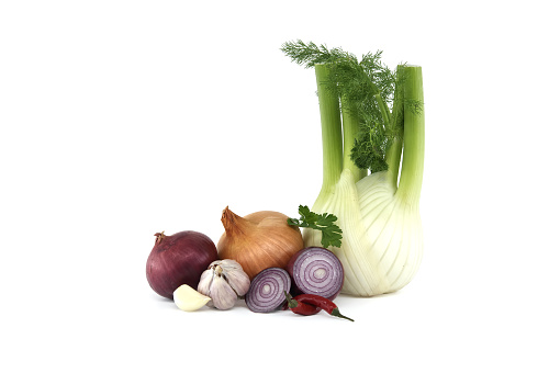 Collection of vegetables consisting red and yellow onions, green fennel, red chili peppers and bulb of garlic isolated on a white background