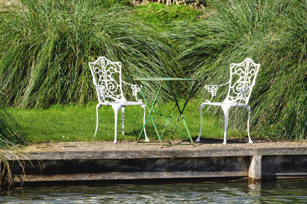 chairs table by the waters of the river cam cambridge, house garden in cambridgeshire, england, united kingdom, great britain, europe, spring season day, uk - usa restaurant flower bed beauty in nature imagens e fotografias de stock