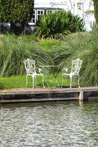 chairs table by the waters of the river cam cambridge, house garden in cambridgeshire, england, united kingdom, great britain, europe, spring season day, uk - usa restaurant flower bed beauty in nature imagens e fotografias de stock