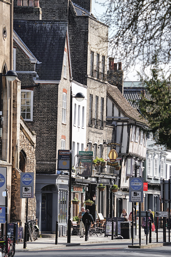 Central Cambridge, Cambridgeshire, England, United Kingdom, Great Britain, Europe. March 18, 2024. The photo captures a street view in an urban environment in Britain, with pedestrians walking along the road. The cityscape showcases distinctive British buildings. It was taken on the Magdalene Bridge located at Bridge St (It runs between Magdalene Street at the junction with Thompson's Lane to the northwest and Sidney Street at the junction with Jesus Lane to the southeast), in Cambridge CB2 1UJ, United Kingdom.