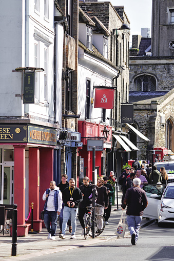 Central Cambridge, Cambridgeshire, England, United Kingdom, Great Britain, Europe. March 18, 2024. The photo captures a street view in an urban environment in Britain, with pedestrians walking along the road. The cityscape showcases distinctive British buildings. It was taken on the Magdalene Bridge located at Bridge St (It runs between Magdalene Street at the junction with Thompson's Lane to the northwest and Sidney Street at the junction with Jesus Lane to the southeast), in Cambridge CB2 1UJ, United Kingdom.