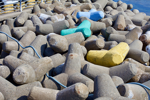 Goseong County, South Korea - July 30, 2019: Predominantly gray-colored tetrapods line the breakwater at Ayajin Port, with a few standout pieces painted in vibrant shades of green, yellow, and blue, adding a pop of color to the coastal defense structure.