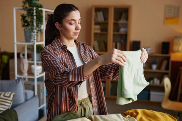 istock Smiling Young Woman Folding Clothes on Laundry Day 2098126038