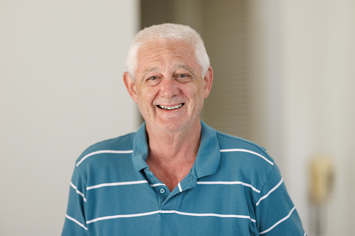 Smiling senior man with white hair indoors.
