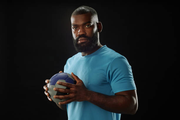 istock Black Football Player Holding Ball 2098154340