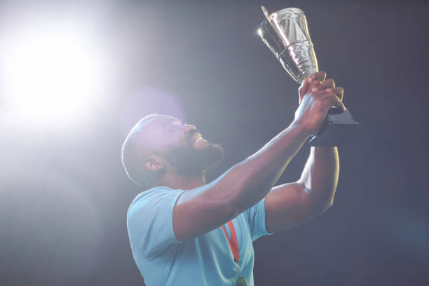 istock Black Sportsman Holding Trophy Cup and Cheering 2098154372