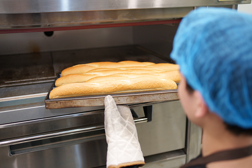 Taking baguette out of oven close-up
