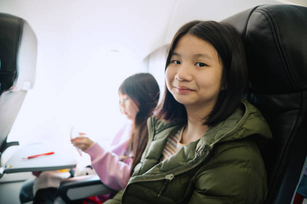 istock Asian girls looking at camera while traveling on plane 2098196648