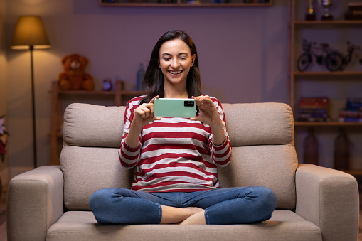 Young woman using photo sitting on sofa at home