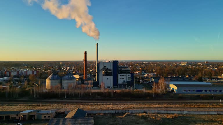 Drone shot of industrial zone with thick smog and burning fossil fuels at sunset