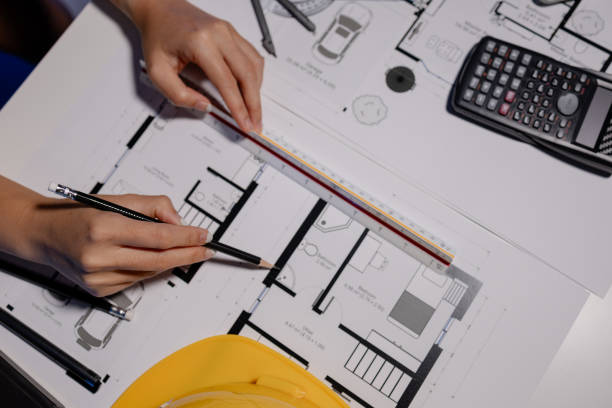 istock An engineer is working in a private office with documents spread across the table, An architect is carefully analyzing blueprints with various tools to get the best results before sending to client. 2098319189