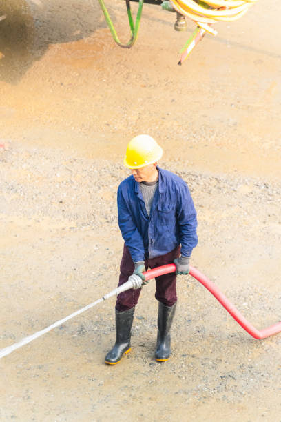 istock Man using water hose to clean the ground 2098321310