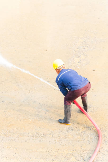istock Man using water hose to clean the ground 2098322393
