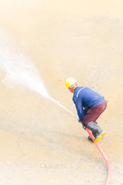 istock Man using water hose to clean the ground 2098322394