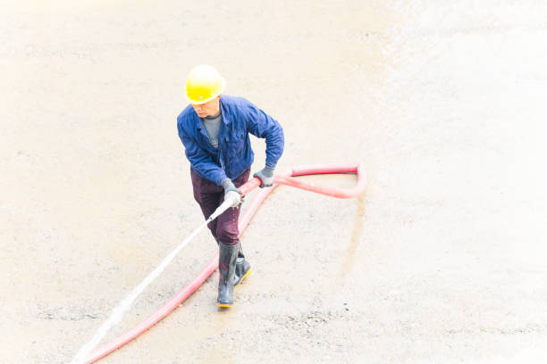 Man using water hose to clean the ground
