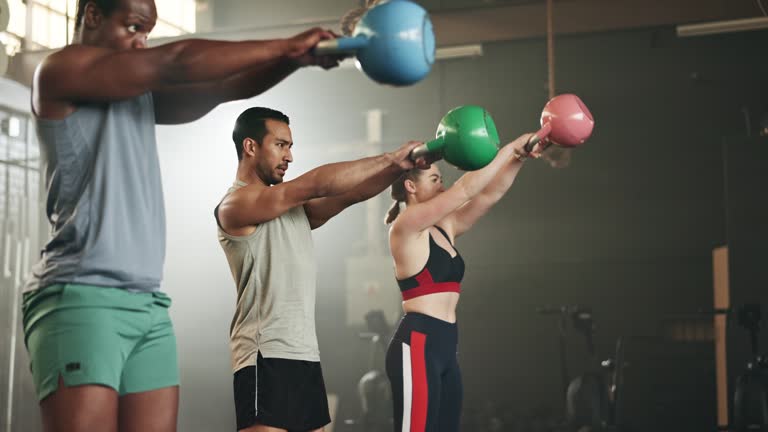 Group, fitness and weightlifting with kettlebell at gym in workout class, exercise or training together. Personal trainer with active people in muscle sports or lose weight at indoor health club