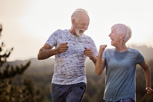 Happy mature couple communicating while running in nature. Copy space.