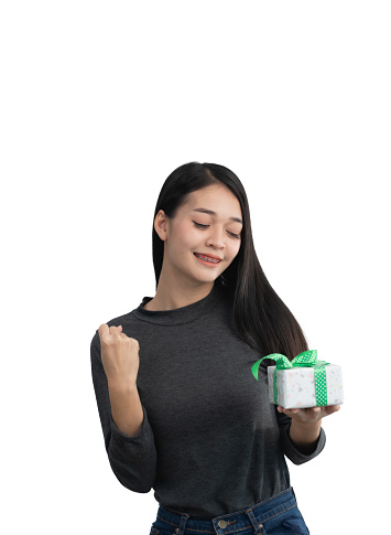 A woman is holding a white gift box and is smiling. She is happy and excited about the gift. Isolated on white background.