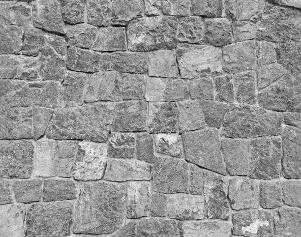 istock Gray stone wall background with copy space in monochrome tone. Grey rock block or tile wallpaper in loft style. Exterior design and pattern in black and white tone. 2098399226