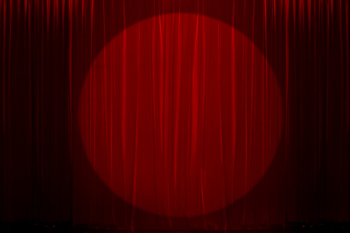 Spotlight on red curtain for Theatre, film festival, award-winning celebration, Nightclub, or cabaret show. Presentation of a classic and luxurious work with performing arts.