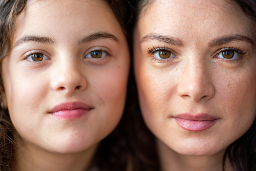 Close-up portrait of a mother and daughter looking at camera