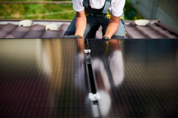 Workers building solar panel system on roof of house. Men installing photovoltaic solar module stock photo