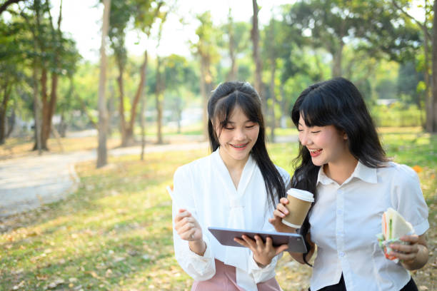 istock Smiling female coworkers using digital tablet and discussing project at the park 2098431562