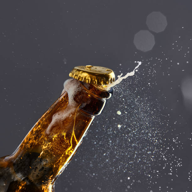 istock Bottle with lager, foamy, bubbled beer opening against gray background with bokeh effect 2098434339