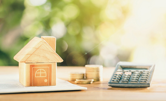 close up house's model on banking account book with calculator, coin and pencil on table for planning of home loan mortgage refinance or retention interest rates , business and financial concept.